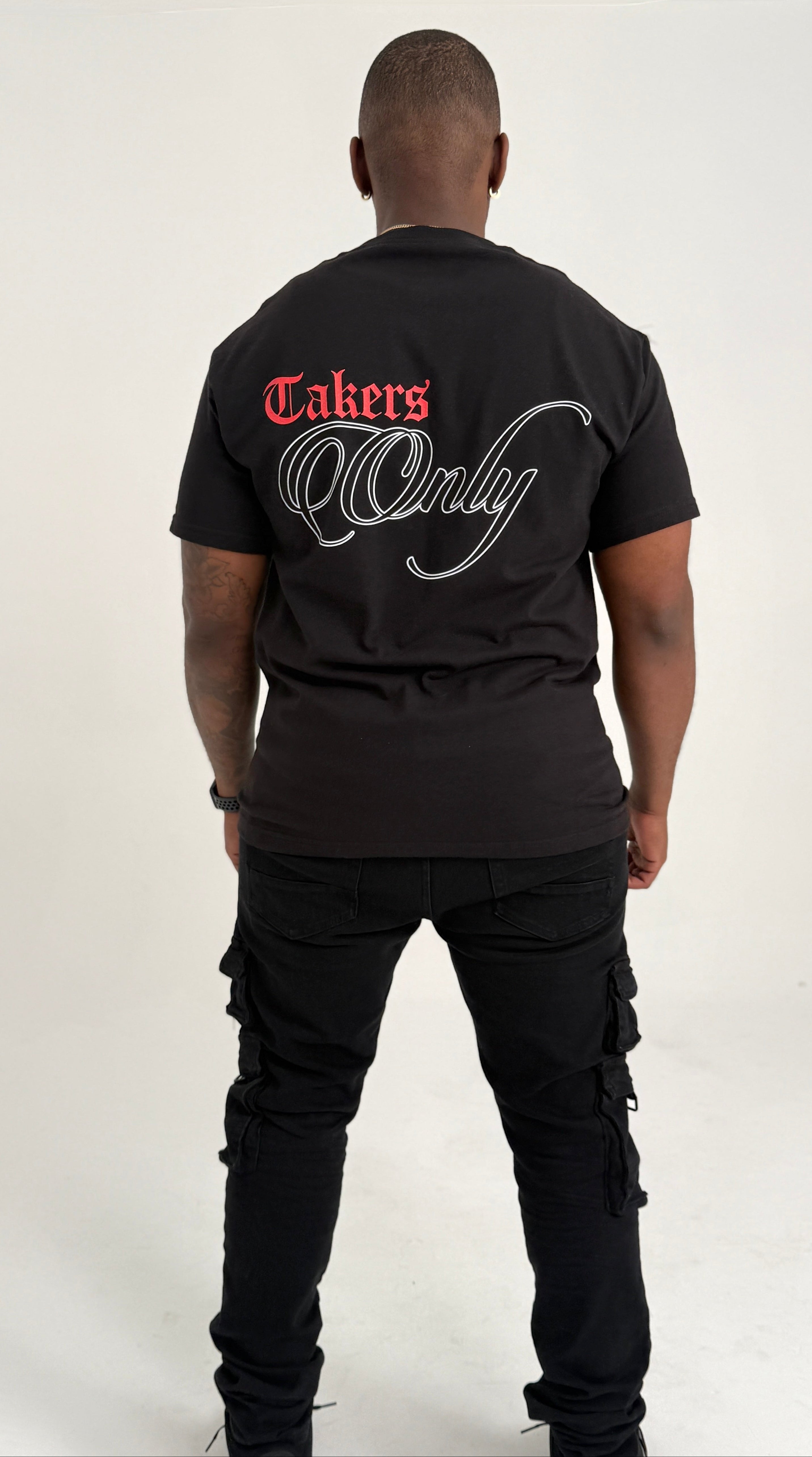 Person wearing a black t-shirt with 'Takers Only' text on the back, standing against a white background